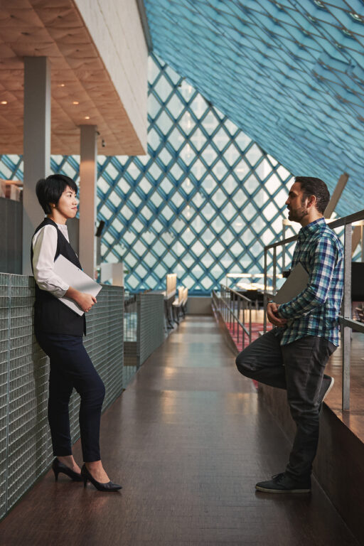 Woman and man holding laptops having a conversation in the Seattle Public Library.
