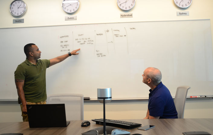 Eric Mendis and Gary Ryan look over a whiteboard.