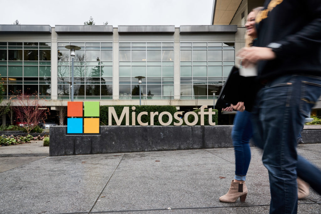 Young professionals walk in front of the Microsoft sign on Microsoft campus