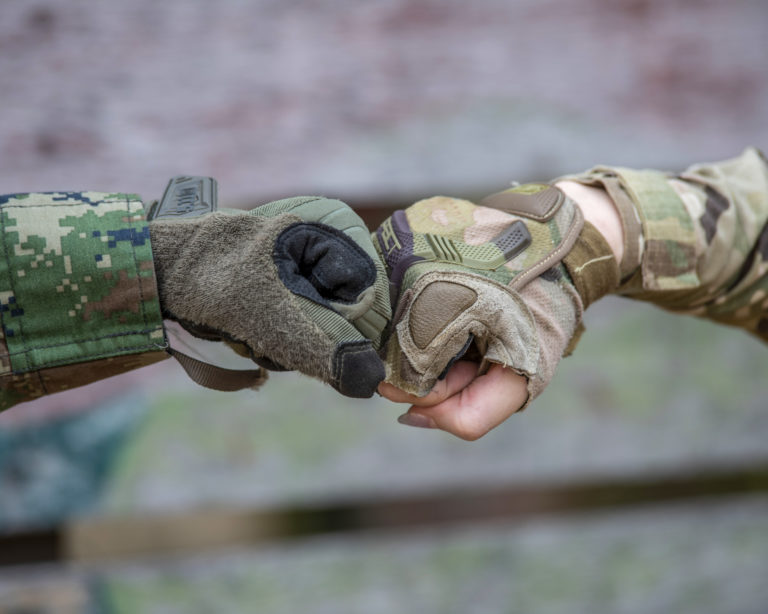 Service members with different uniforms fist-bump.
