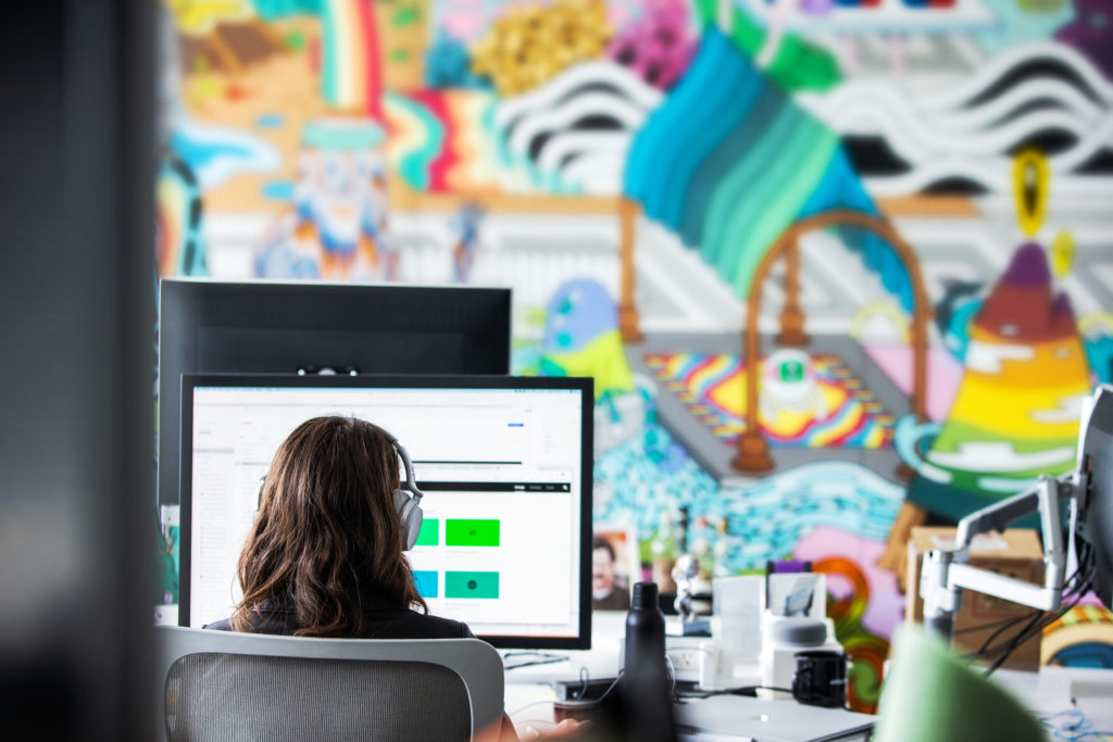 A tech industry employee works at her desk while wearing headphones in U.S. office.
