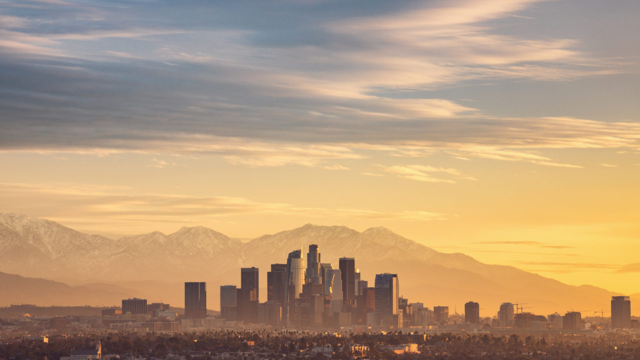 Morning light at sunrise of Downtown Los Angeles with snowy mountains in the background.