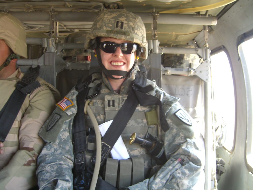 Uniformed female service member in plane hanger smiles at camera.