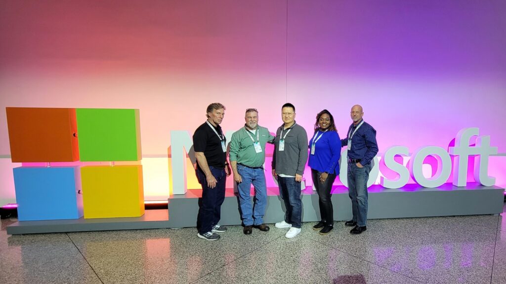 MSSA alumni Meka L. and 4 colleagues stand in front of the Microsoft corporate logo