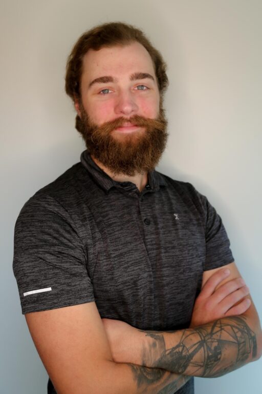 Bearded professional man crosses arms and looks at the camera.