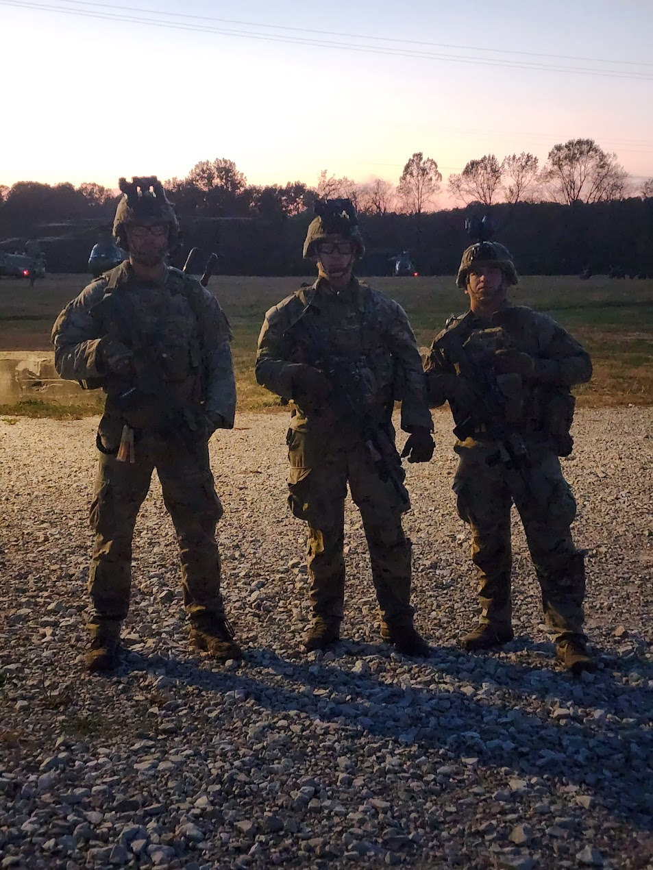 Three soldiers face the camera with the sun behind them
