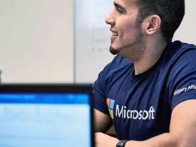 Young man in Microsoft shirt smiles in computer lab